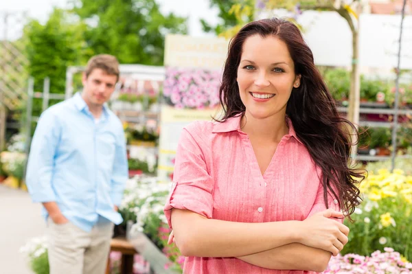 Усміхнена жінка стоїть в садовому центрі — стокове фото
