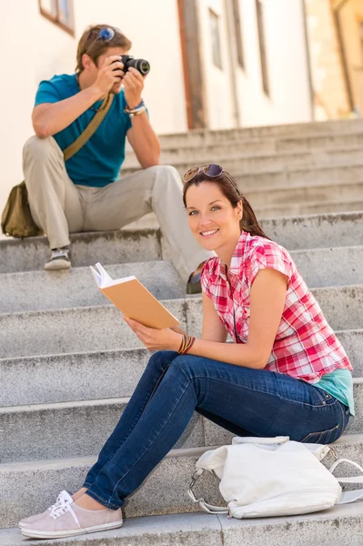 Žena sedí na schodech čtení člověka fotografování — Stock fotografie