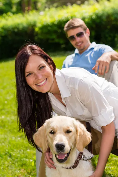 Paret sitter med golden retriever i park — Stockfoto