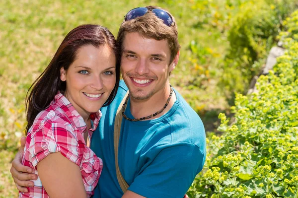 Unga lyckliga par omfattar i solig park Royaltyfria Stockbilder