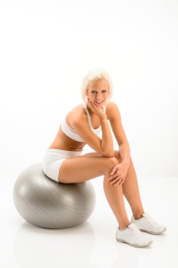 Pilates topu beyaz fitness üzerinde oturan kadın
