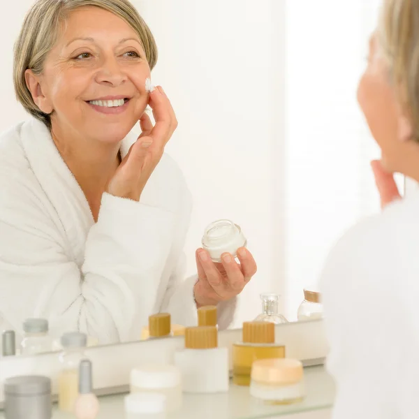 Senior woman apply anti-wrinkles cream look mirror — Stock Photo, Image