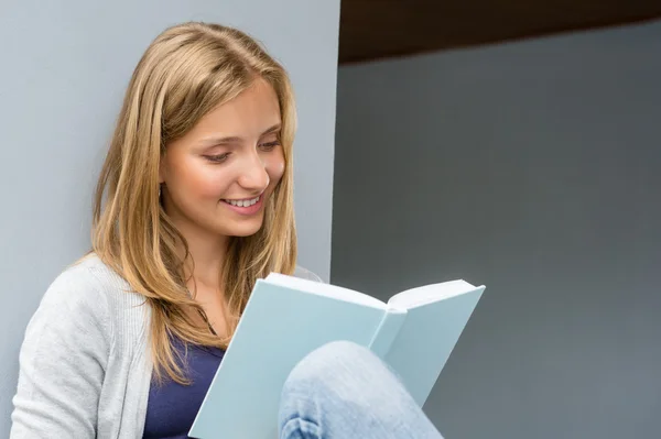 Student meisje lezen boek vergadering buiten glimlachen — Stockfoto