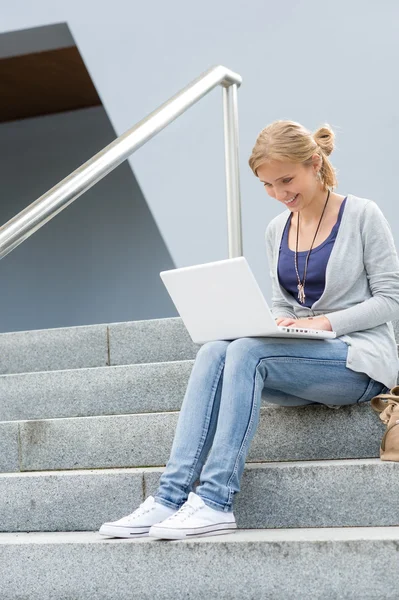 Estudiante chica en escaleras con portátil sonriendo —  Fotos de Stock