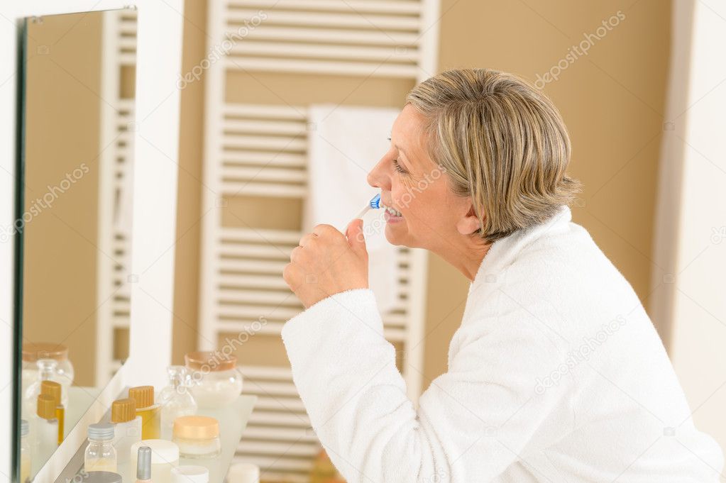 Senior woman brushing teeth in bathroom