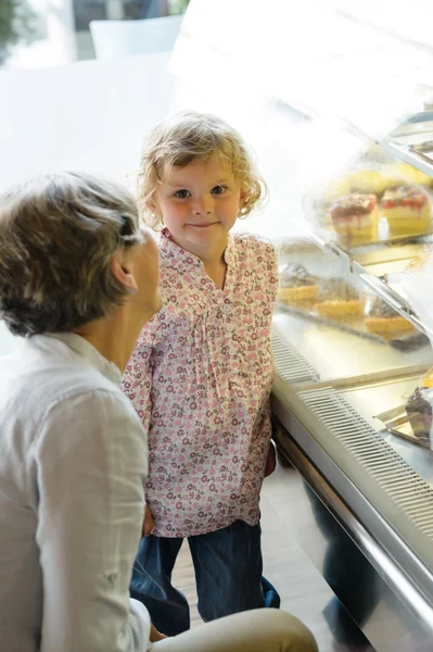 Mujer con niña niña elegir torta panadería —  Fotos de Stock