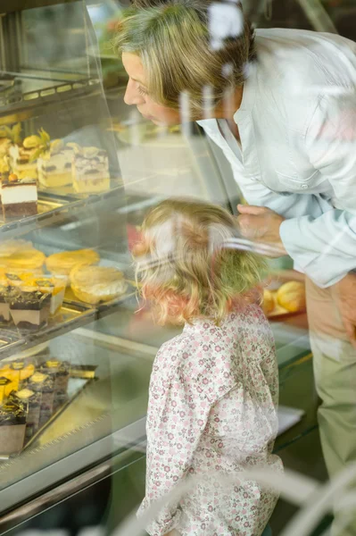 Barnbarn och mormor tittar på kakor café — Stockfoto