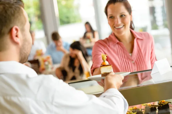 Camarero dando plato de pastel de mujer en la cafetería — Foto de Stock