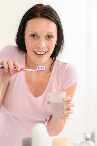 Mulher escovando dentes segurando vidro de água — Fotografia de Stock