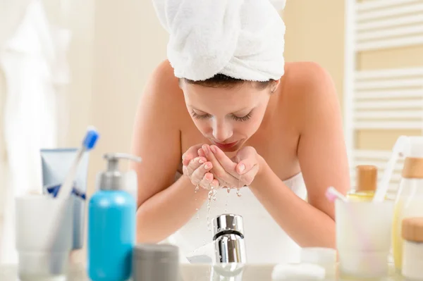 Žena mytí obličeje nad umyvadlem — Stock fotografie
