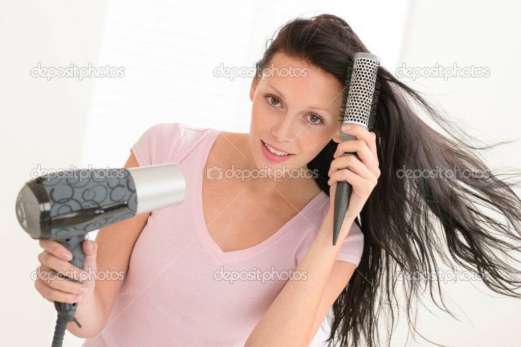 Woman blow-drying hair using round hairbrush