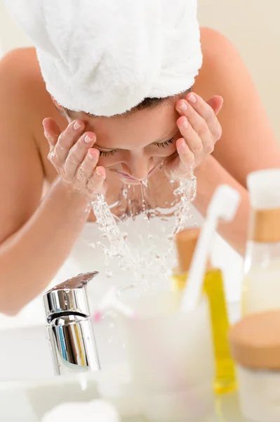 Vrouw opspattend water gezicht in badkamer — Stockfoto