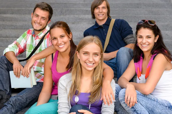 Studenti sedí na schodech školy s úsměvem teens — Stock fotografie