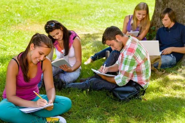 Studenti sedí v parku studium, čtení, psaní — Stock fotografie