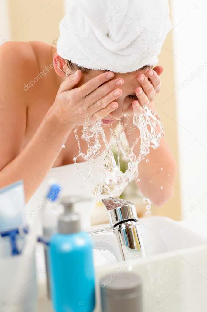 Splash in bathroom woman cleaning face