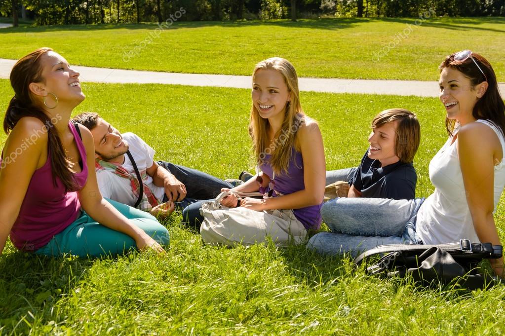 adolescentes sentados en el césped en el parque hablando — Foto de