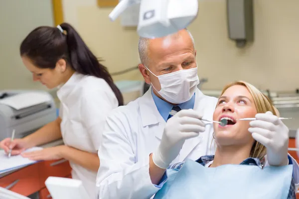 Dentista fazendo procedimento em jovem paciente mulher — Fotografia de Stock