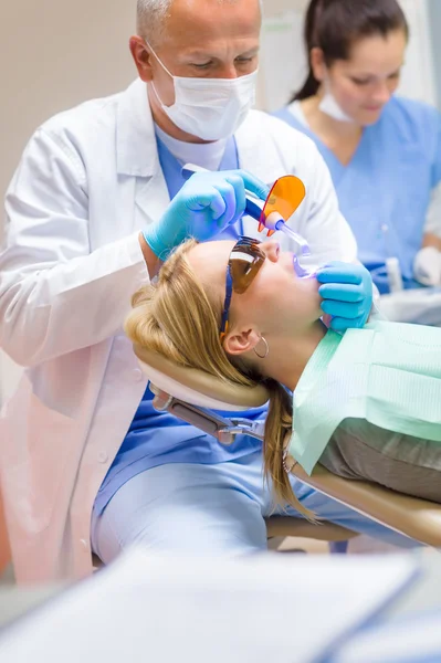 Dentista use lâmpada paciente feminino — Fotografia de Stock