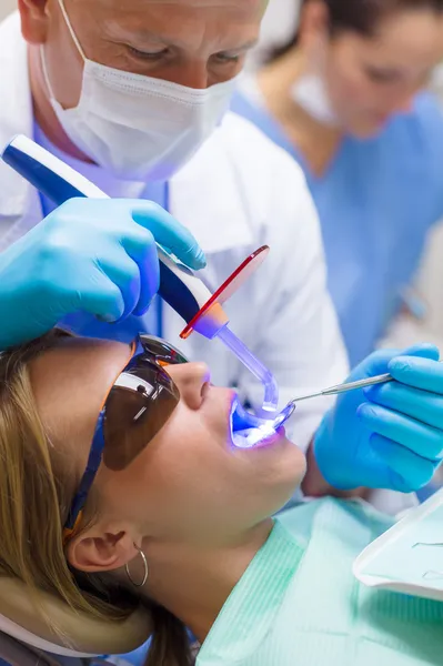 Dentista usar lâmpada UV paciente feminino — Fotografia de Stock