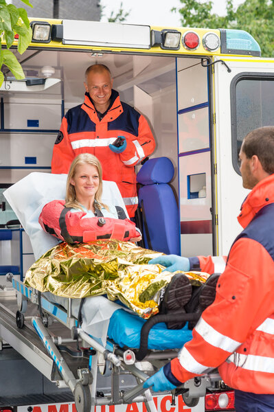 Paramedics helping woman on stretcher in ambulance