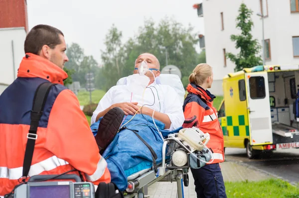 Les ambulanciers avec le patient sur civière ambulance aide — Photo