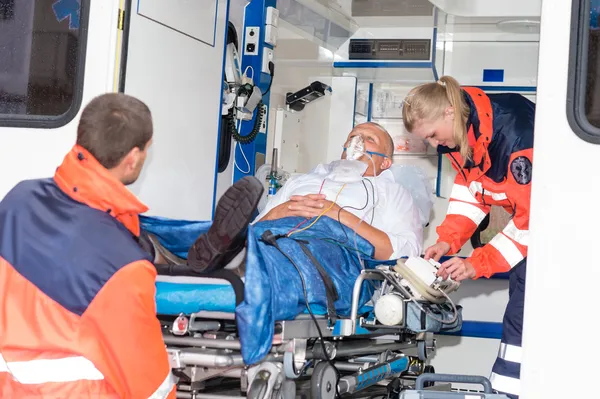 Paramedics putting patient in ambulance car aid — Stock Photo, Image