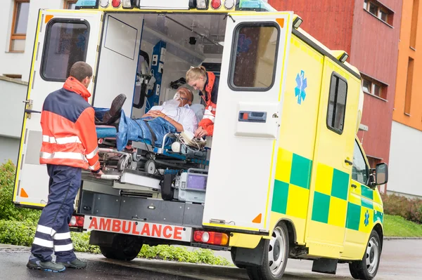 I paramedici mettono il paziente in ambulanza aiuto auto — Foto Stock