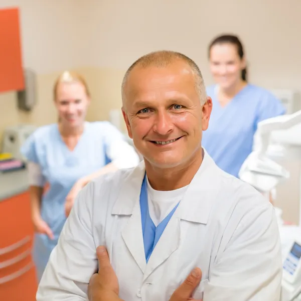 Lachende tandheelkundige chirurg poseren met verpleegkundigen Stockfoto