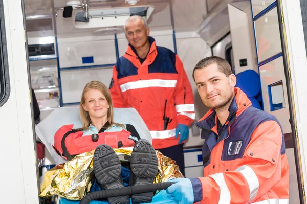 Paramédicos ajudando mulher na maca em ambulância Imagem De Stock