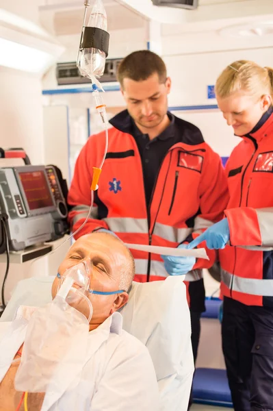 Los paramédicos que leen el electrocardiograma en ambulancia ayudan al paciente Imagen De Stock