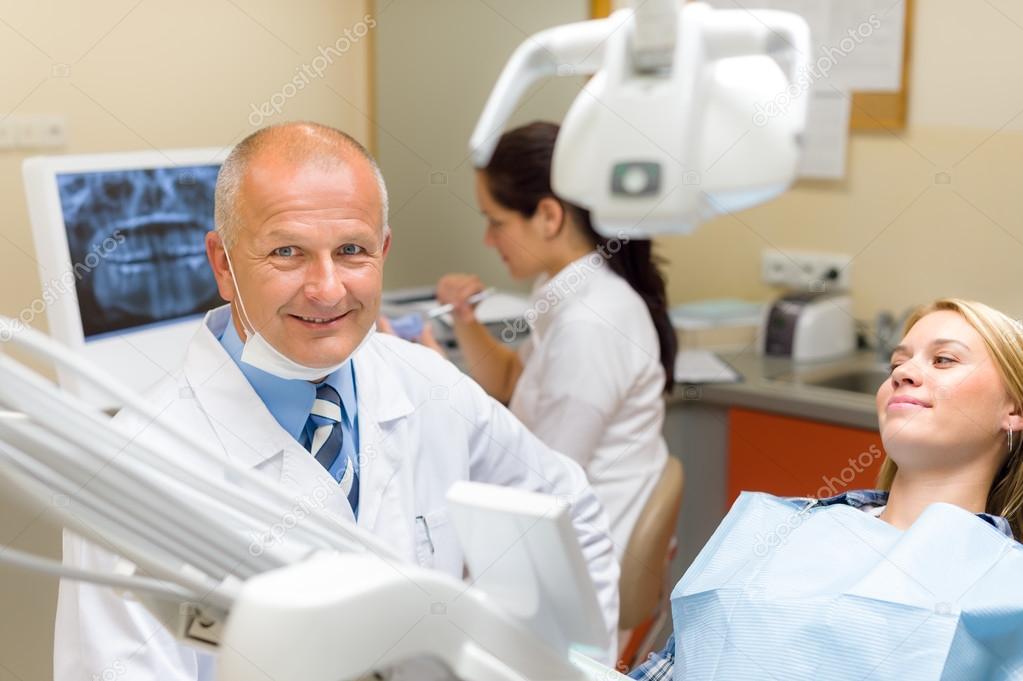 Friendly dentist with female patient dental office