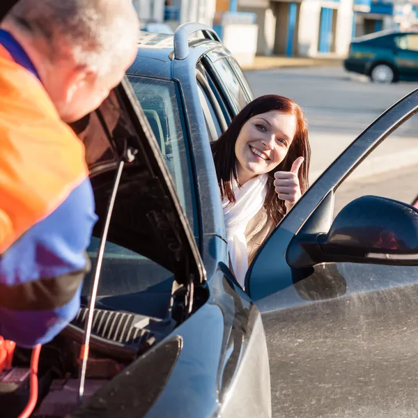 メカニックが車の幸せな女の親指を固定します。 — ストック写真