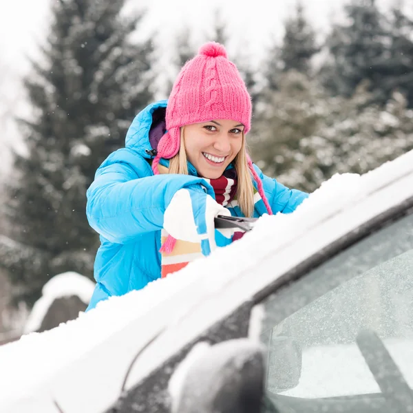 Kvinna rengöring bil vindrutan på snö vinter — Stockfoto