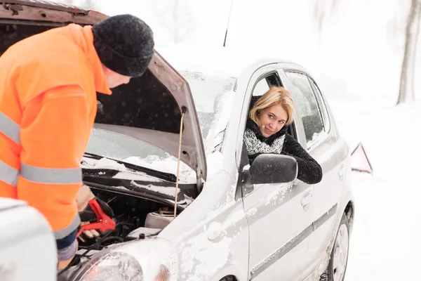 Homem reparando carro da mulher neve assistência inverno — Fotografia de Stock