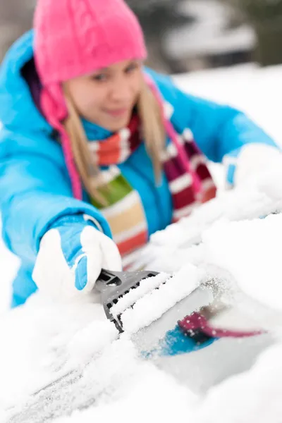 Woman brushing snow from car windscreen winter Stock Image