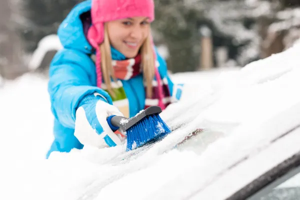 Woman wiping snow car window using brush Royalty Free Stock Photos