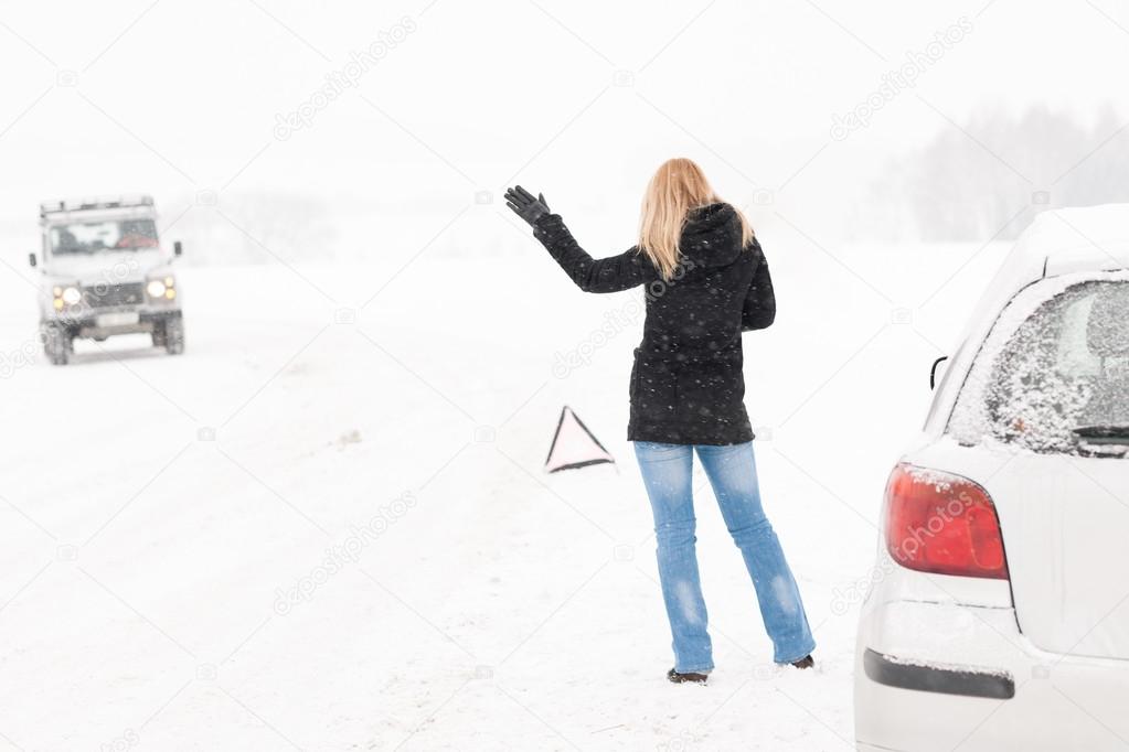 Woman hitchhiking having trouble with car snow