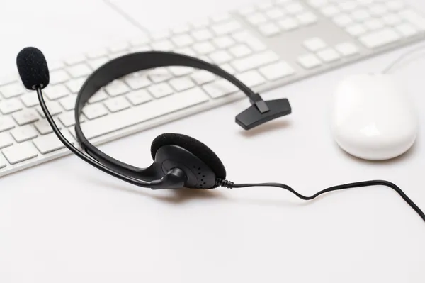 Fones de ouvido preto do escritório no teclado branco — Fotografia de Stock