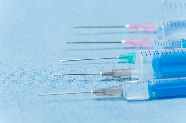 Inyecciones de agujas hipodérmicas sobre tela médica azul — Foto de Stock