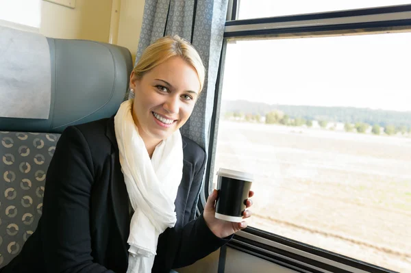 Mulher sorrindo sentado no trem segurando café — Fotografia de Stock