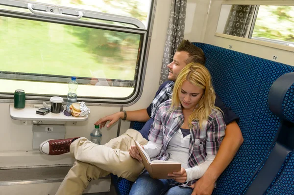 Uomo guardando fuori dalla finestra del treno donna lettura — Foto Stock