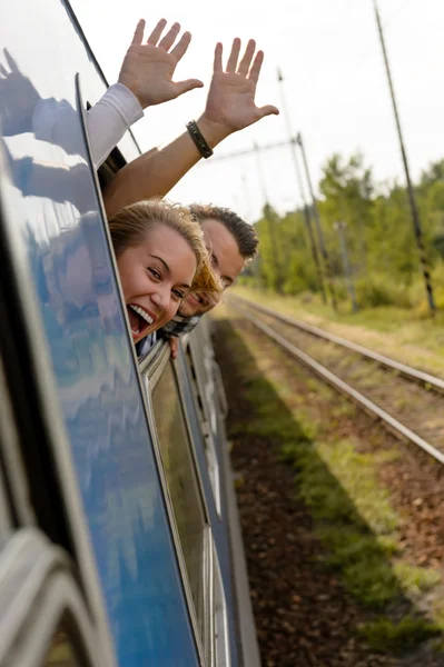 Casal acenando com cabeças para fora da janela do trem — Fotografia de Stock