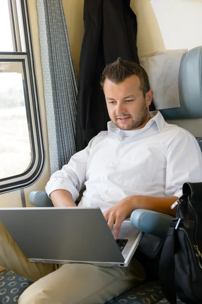 Man sitting in train using laptop computer — Stock Photo, Image