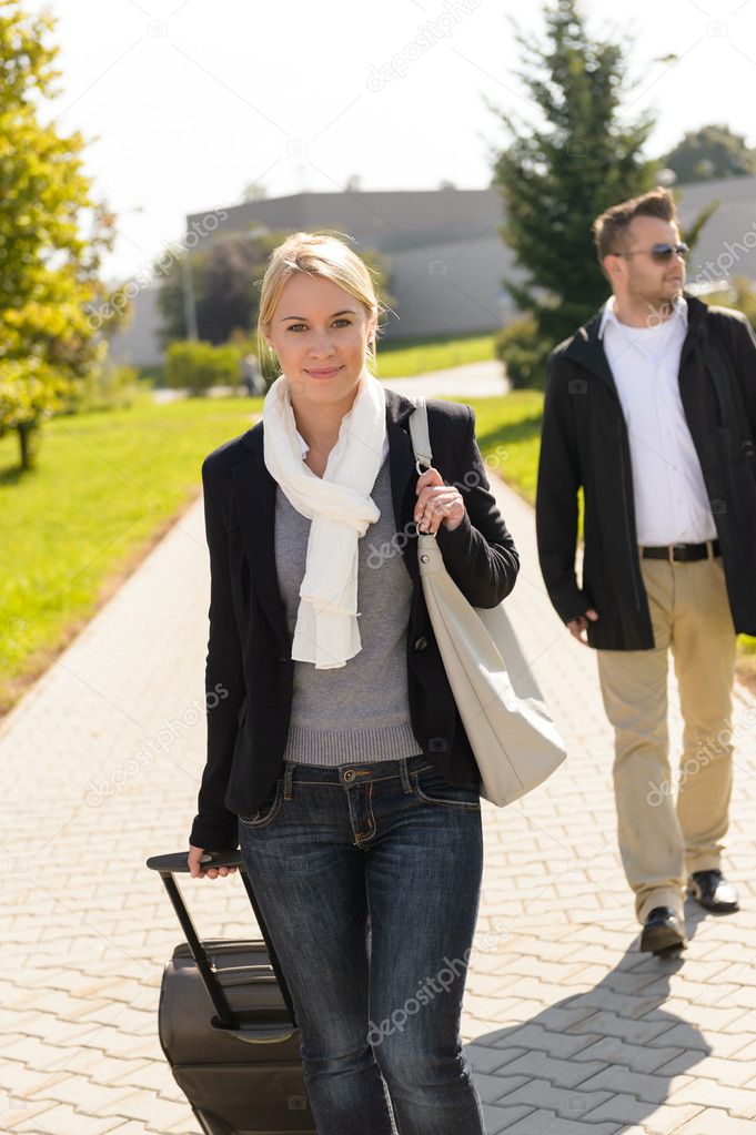 Woman arriving in park with baggage man