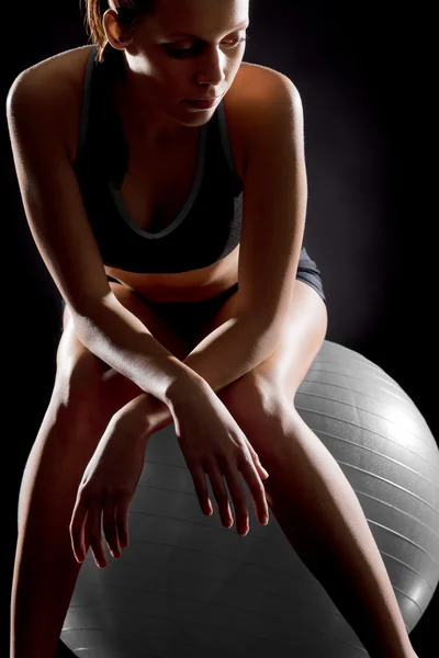 Задумчивая молодая женщина расслабляется на фитнес-мяч — стоковое фото