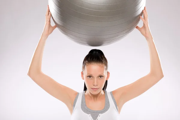 Portrait of young woman exercising with ball — Stock Photo, Image