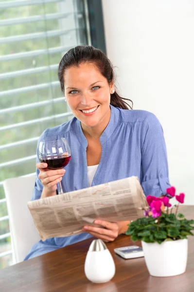 Cheerful woman reading drinking wine newspaper living — Stock Photo, Image