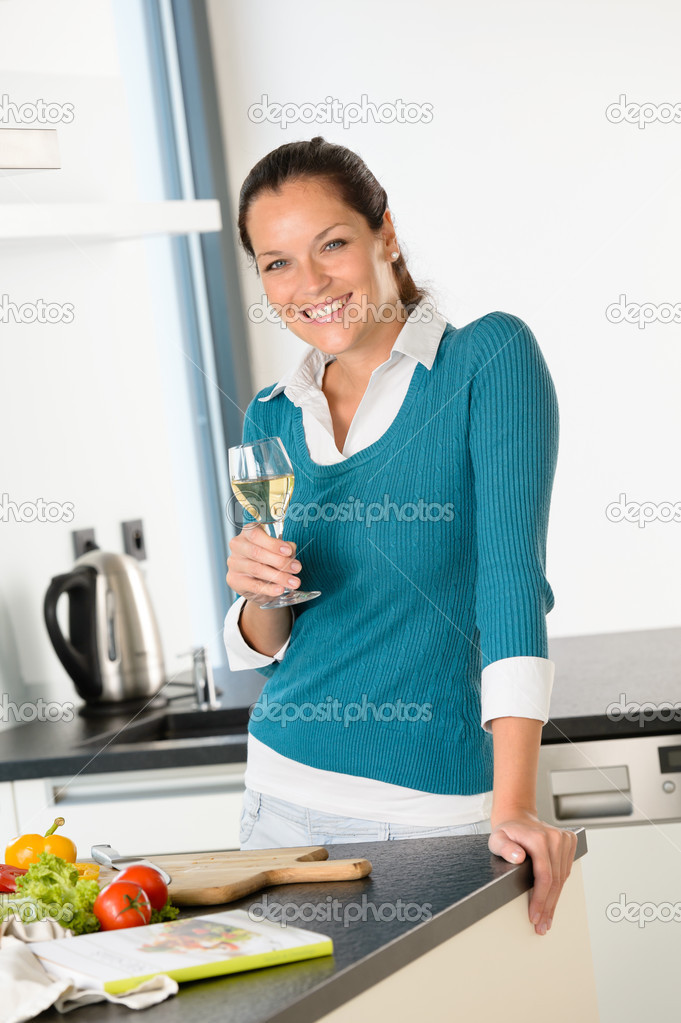 Smiling woman kitchen drinking wine preparing vegetables