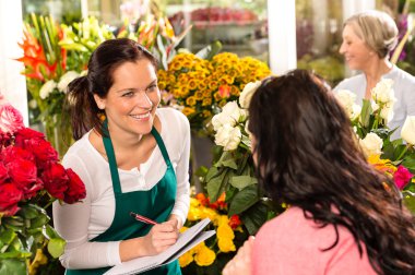 Happy florist writing flower shop talking customer