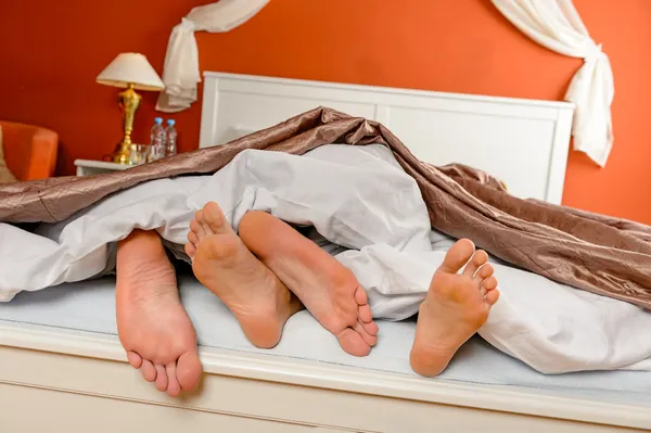 Cochilando casal descalço deitado sob cobre cama — Fotografia de Stock